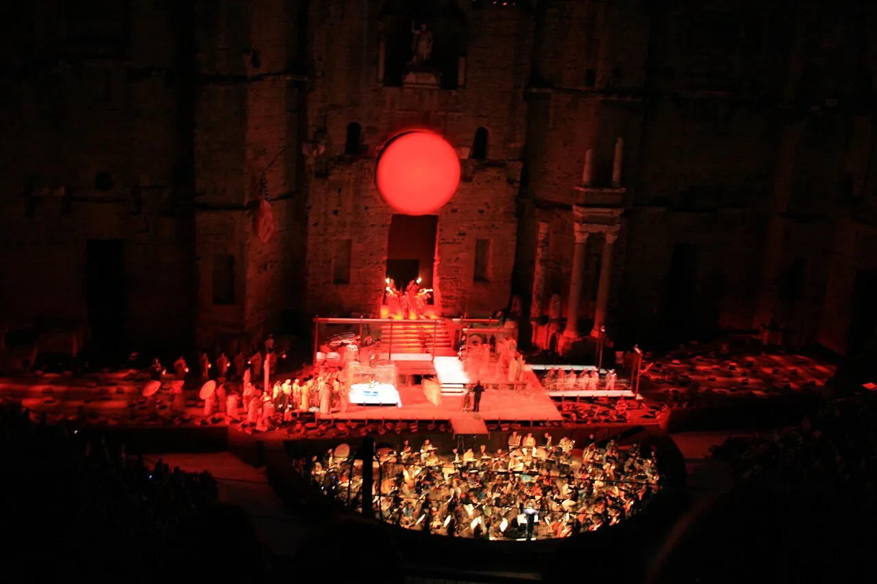 Outdoor cultural performance in Orange beneath a summer evening sky